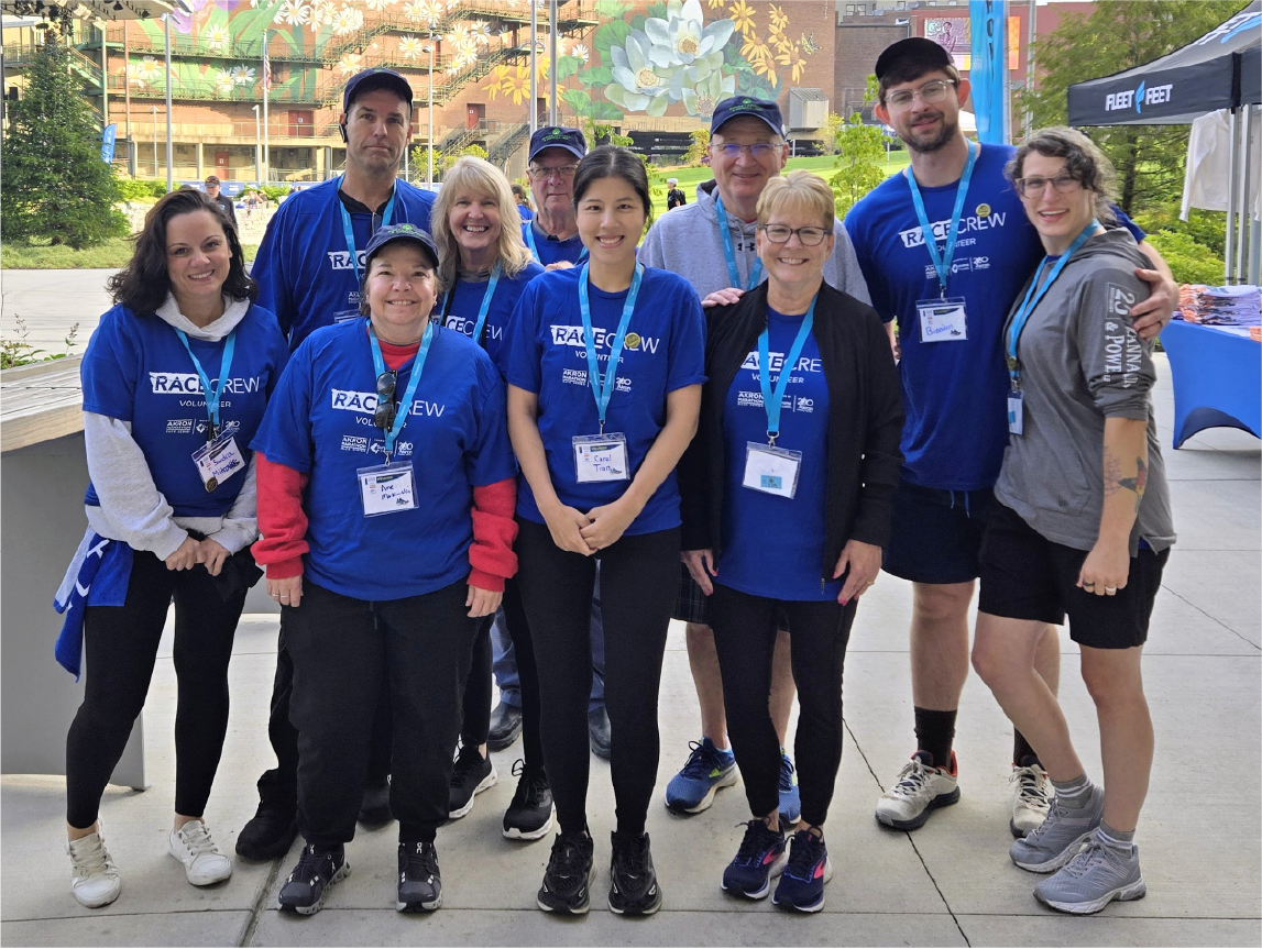 community-volunteers-group-photo Group of smiling volunteers in blue shirts posing together outdoors during a community event.