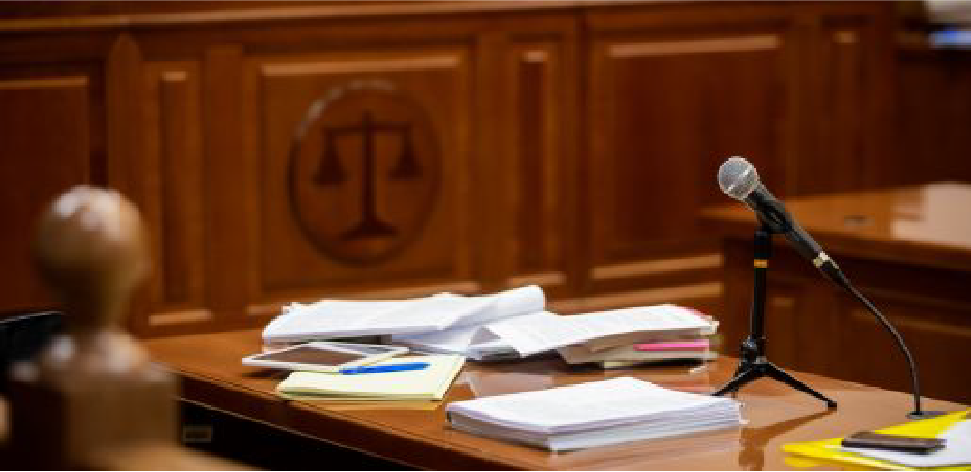 Courtroom desk with a microphone, legal documents, and notepads prepared for a hearing or trial session.