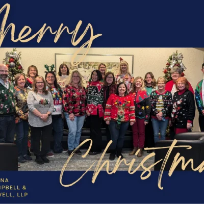 Law firm staff celebrating the holidays in festive Christmas sweaters in an office decorated with trees and lights.